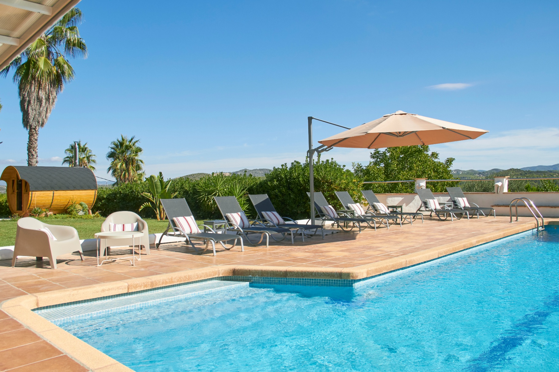 Piscine extérieure avec transats et parasol face au jardin
